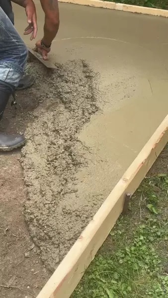 Worker screeding fresh concrete to level the surface