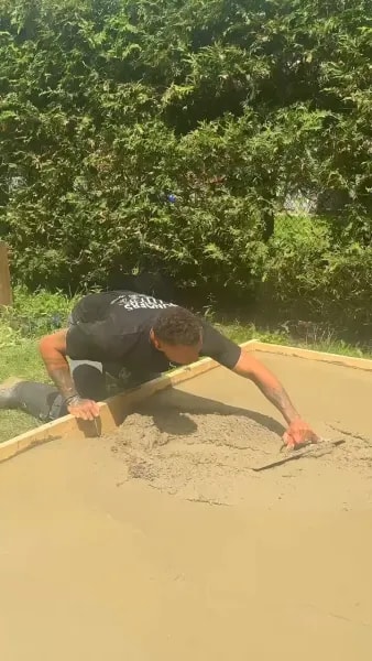 Tradesperson hand-troweling the concrete surface for a smooth finish
