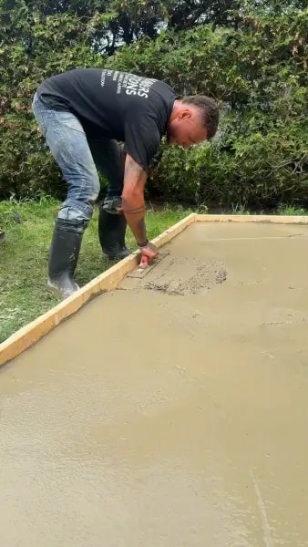 Worker finishing and detailing the edge of a concrete slab