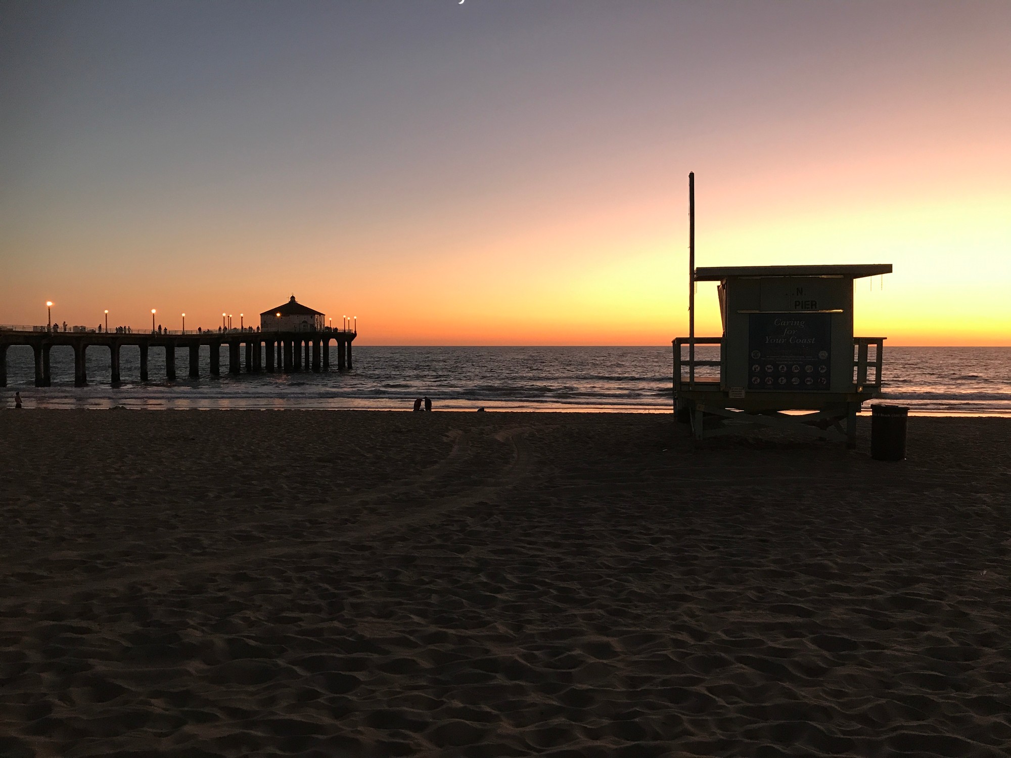 Manhattan Beach pier and lifeguard tower silhouetted against the sunset