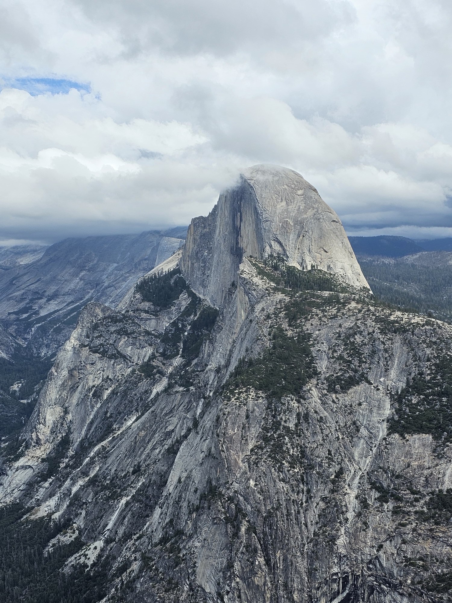 Half Dome seen close up from Glacier Point, with clouds around its summit