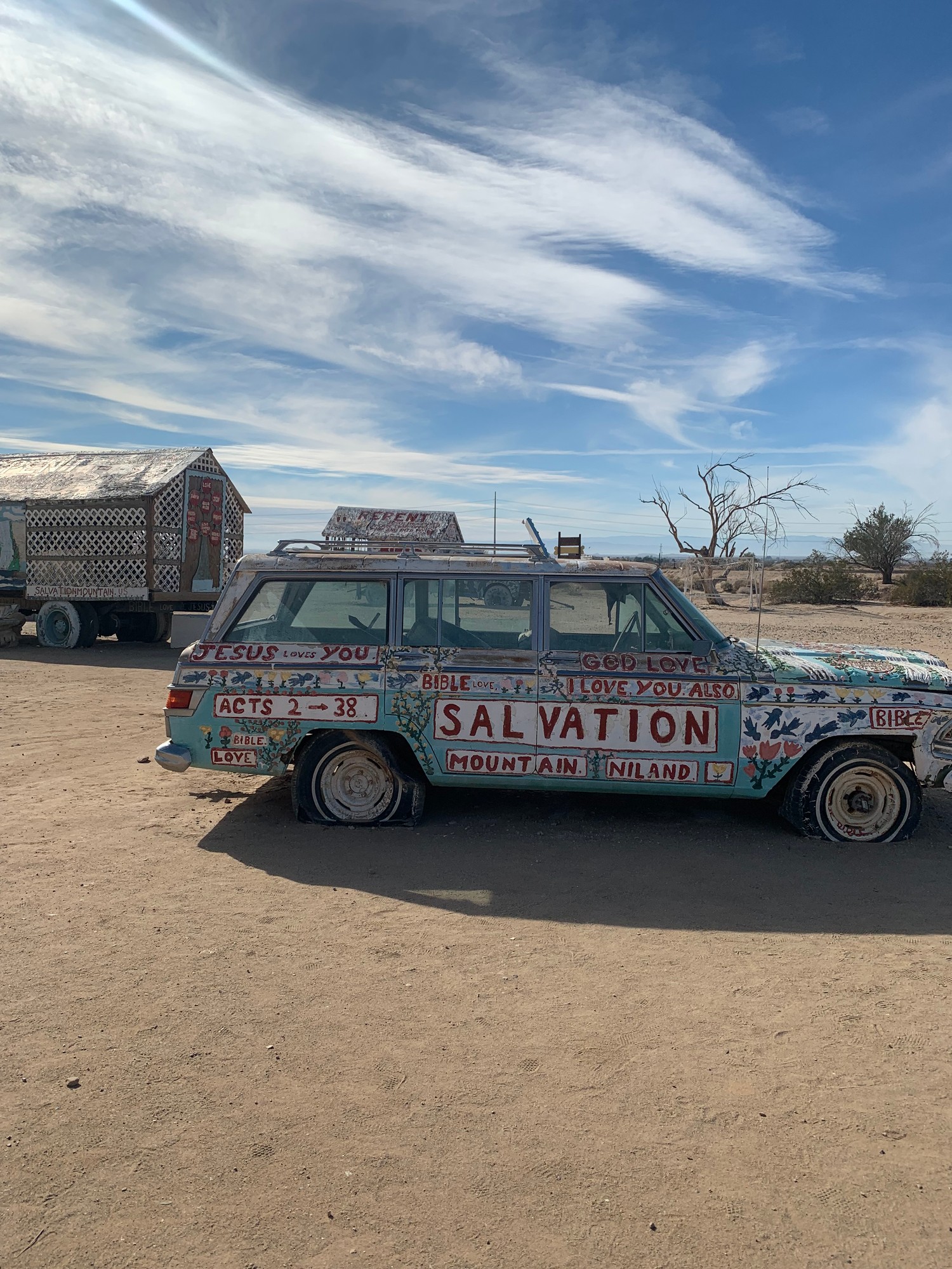 The painted Salvation Mountain jeep parked at the site, with the repentance wagons behind