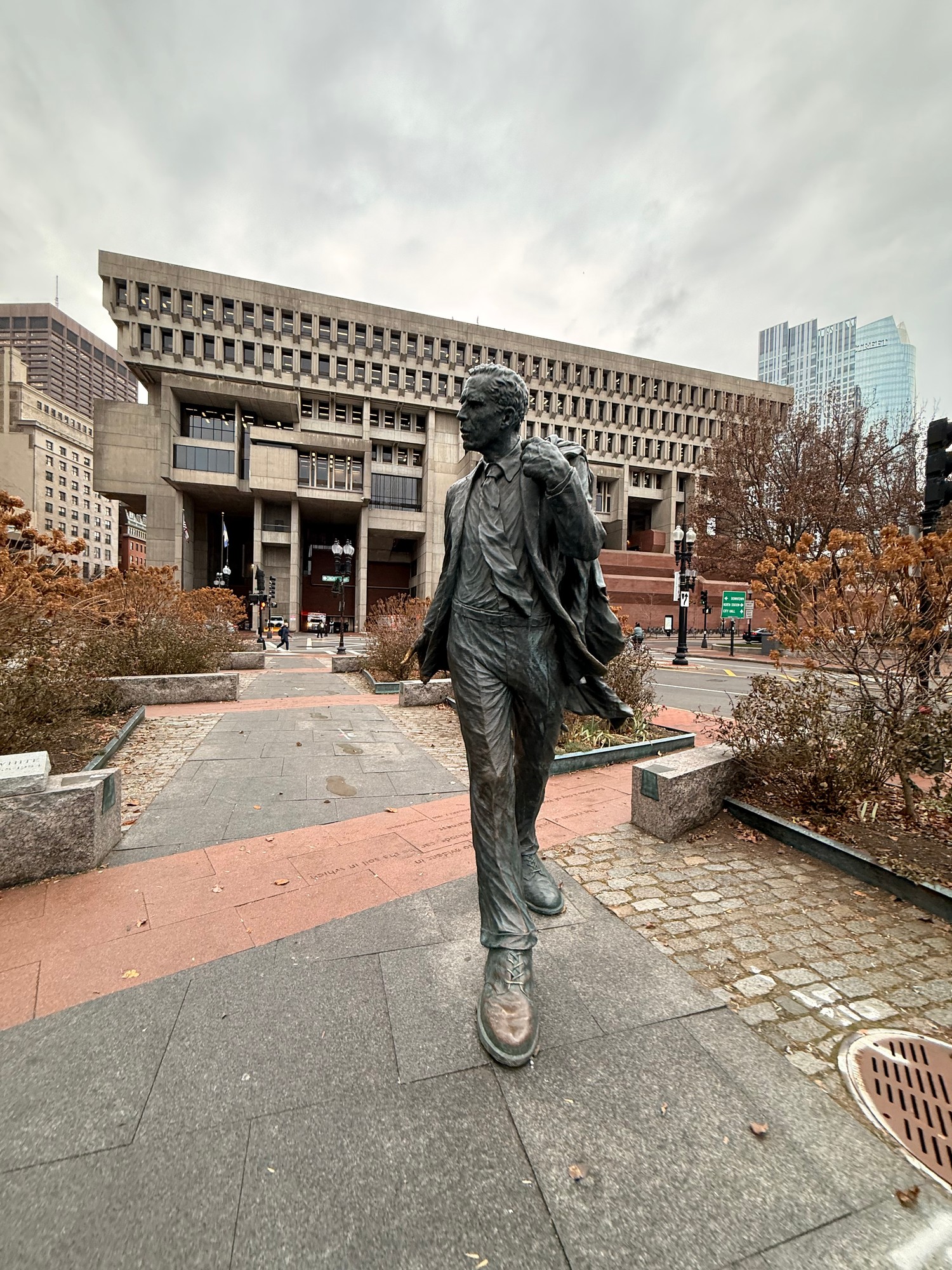 A statue of former Boston mayor Kevin White striding along the Freedom Trail, with Boston City Hall behind