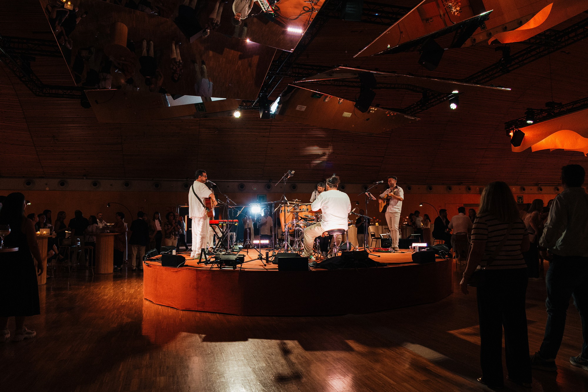 Banda tocando en directo sobre un escenario circular durante una fiesta de empresa