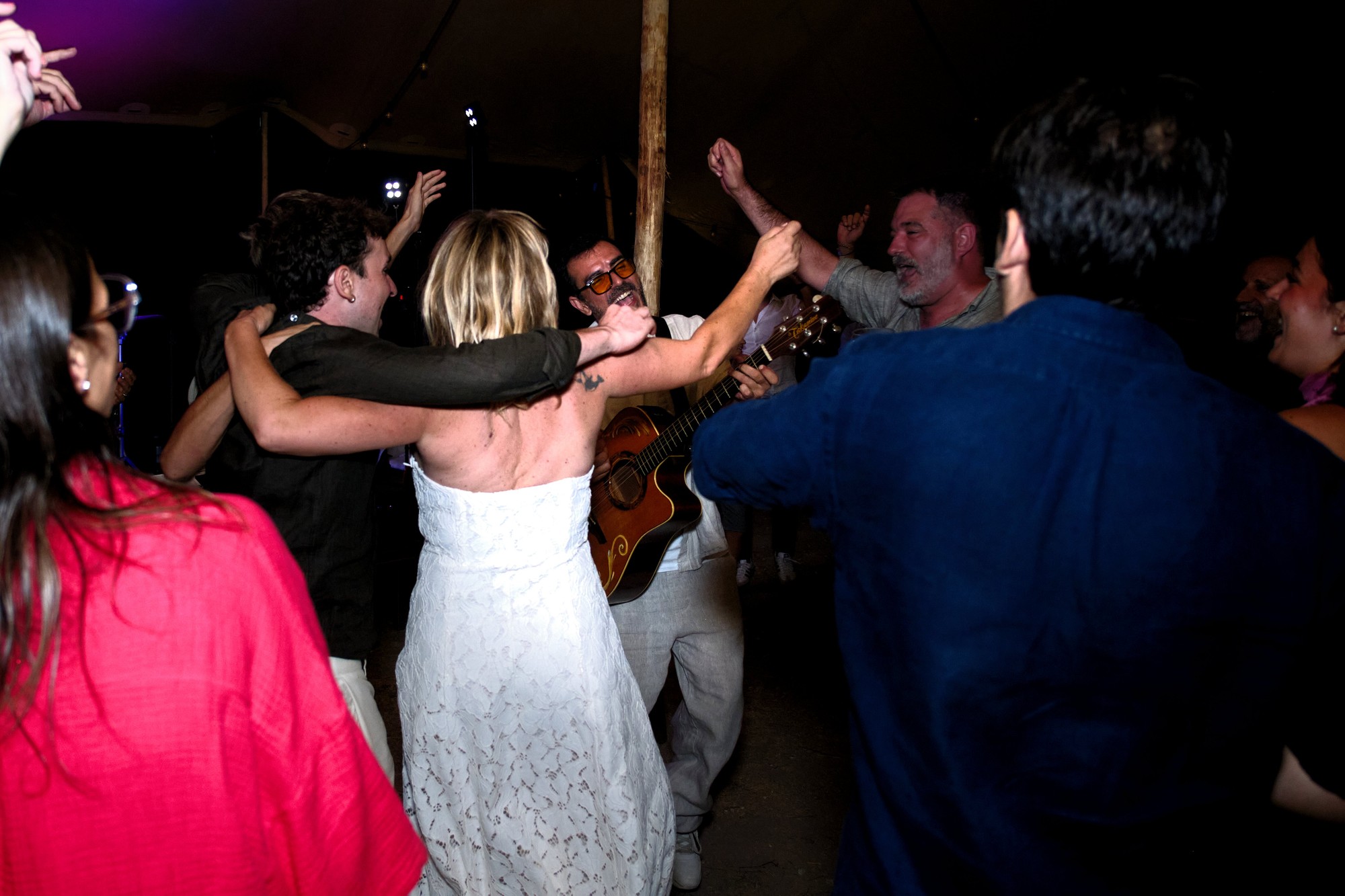 Joan Tena cantando y tocando la guitarra entre los invitados que bailan en una boda de noche