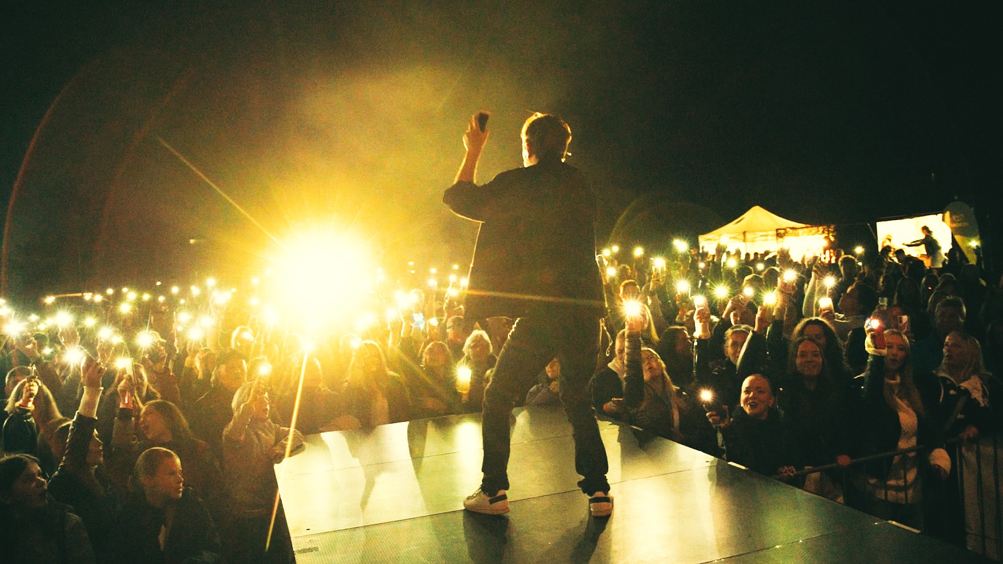 Zpěvák na pódiu s nadšeným publikem a světly