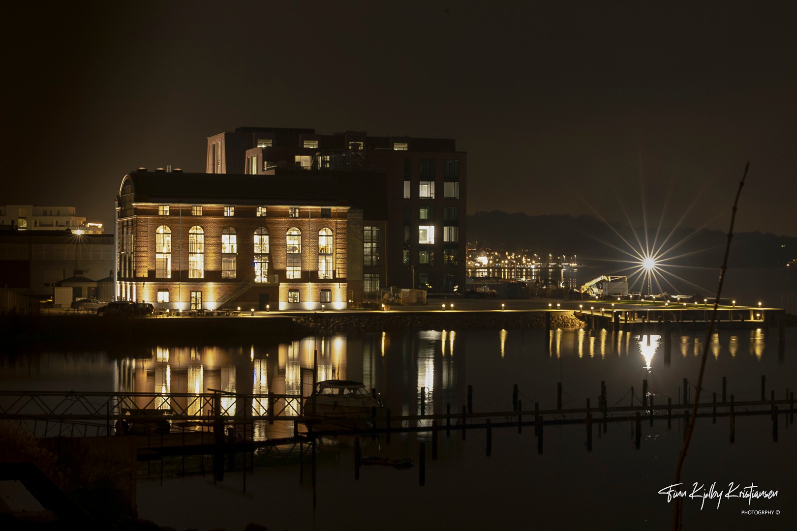 Oplyst bygning ved havnen i aftenlys