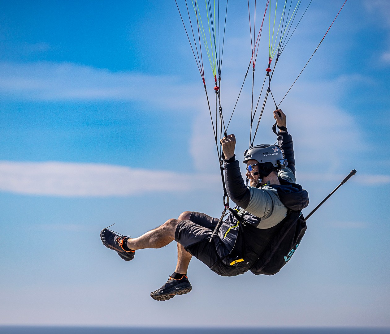 Person, der flyver i paraglider mod en blå himmel