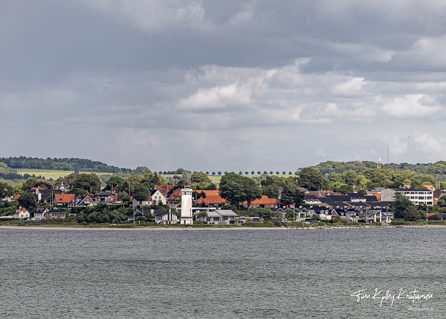 Kystby med fyrtårn under dramatisk himmel