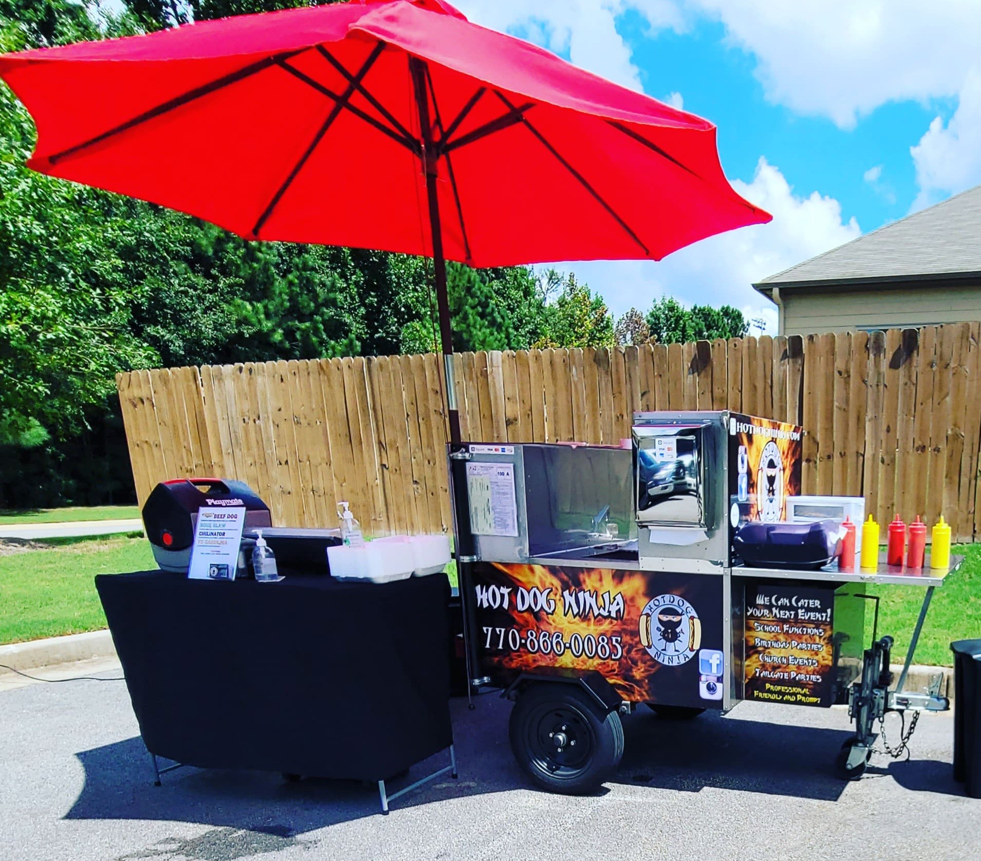 Hot Dog Ninja cart fully set up with red umbrella and menu board