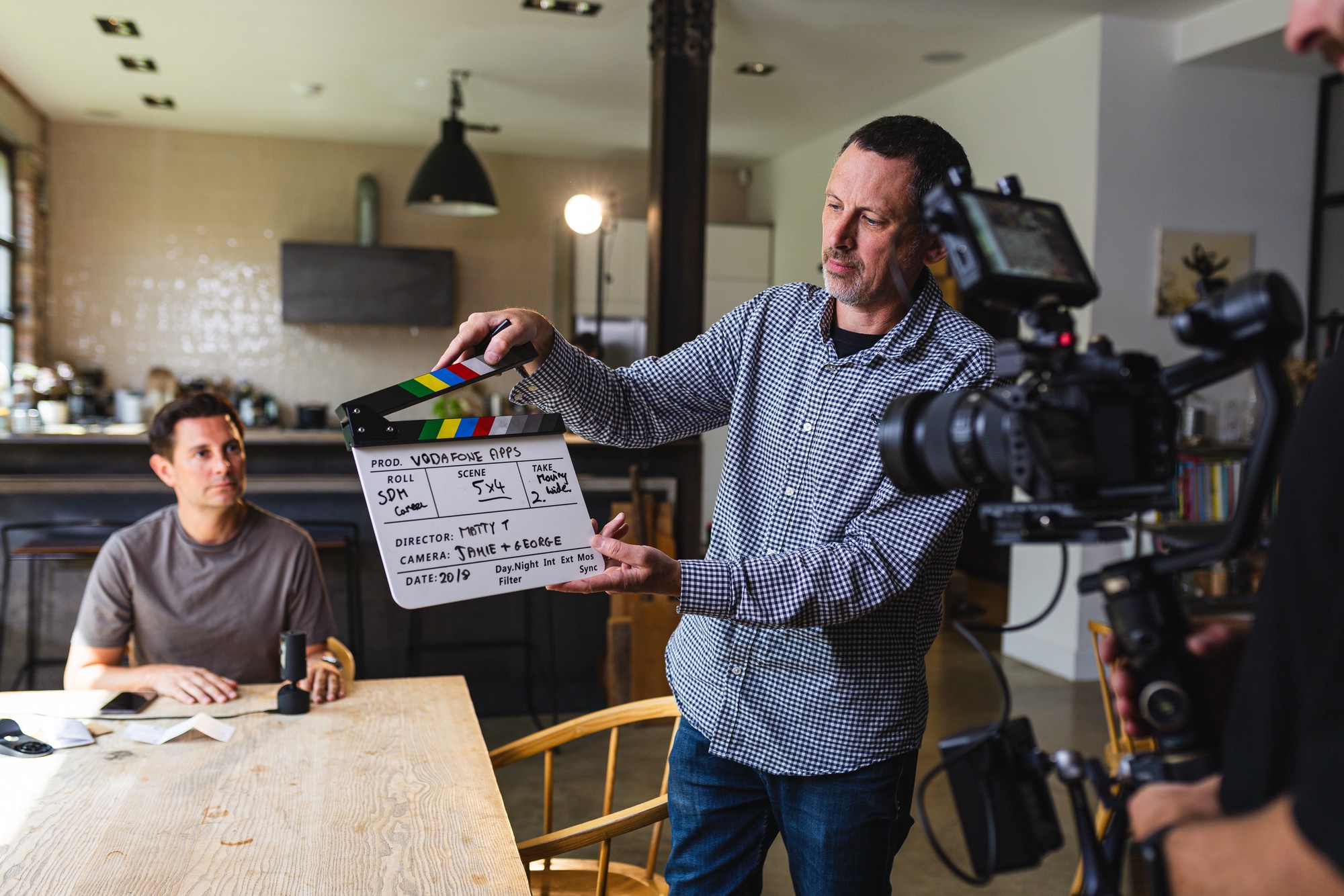 A presenter, camera operator and sound recordist setting up a filmed interview in a bright workshop space