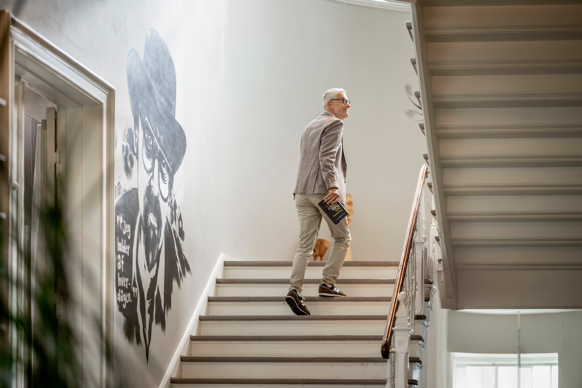 Jean Pierre går op ad en trappe med en bog i hånden
