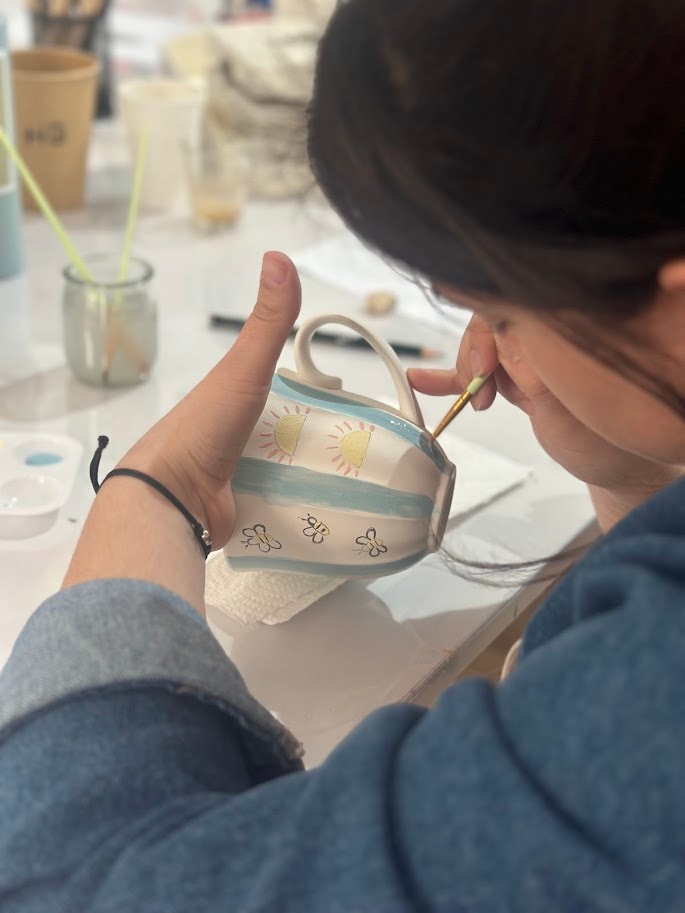 Criança a pintar cerâmica no atelier MitoArte — concentração e criatividade
