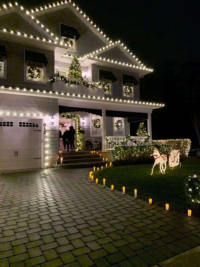 Beautiful home with professional Christmas lights on roofline and decorated yard