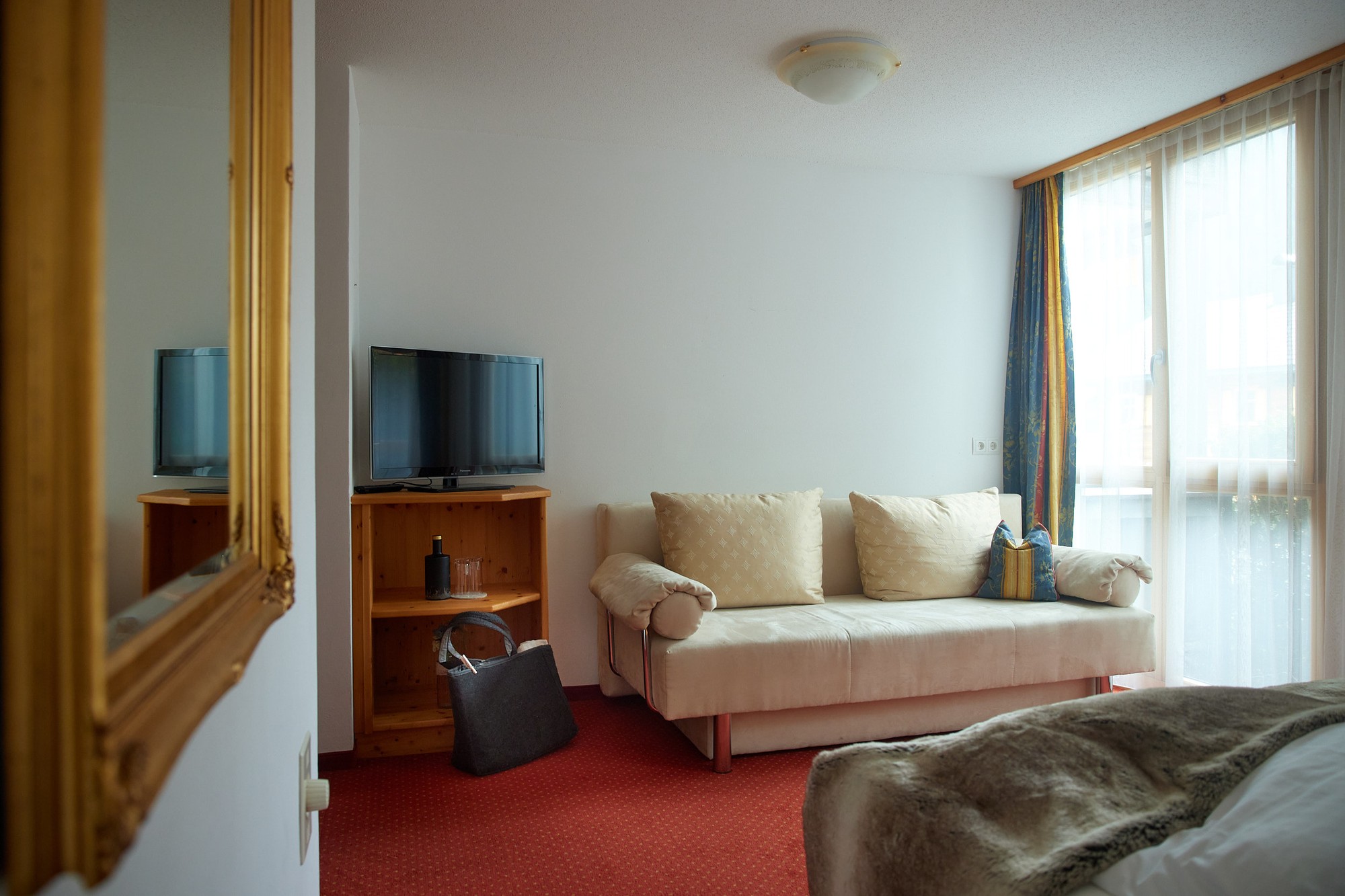 Sitzecke mit Sofa, Fernseher und Balkontür im Doppelzimmer Plus