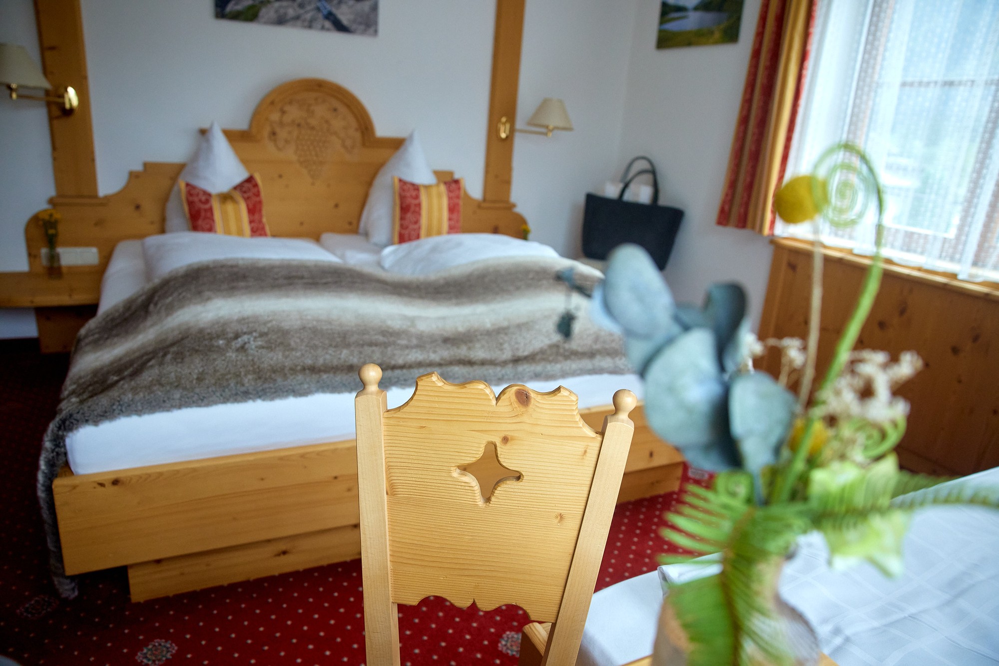 Blick über den Tisch zum geschnitzten Holzbett im Familienzimmer für 3