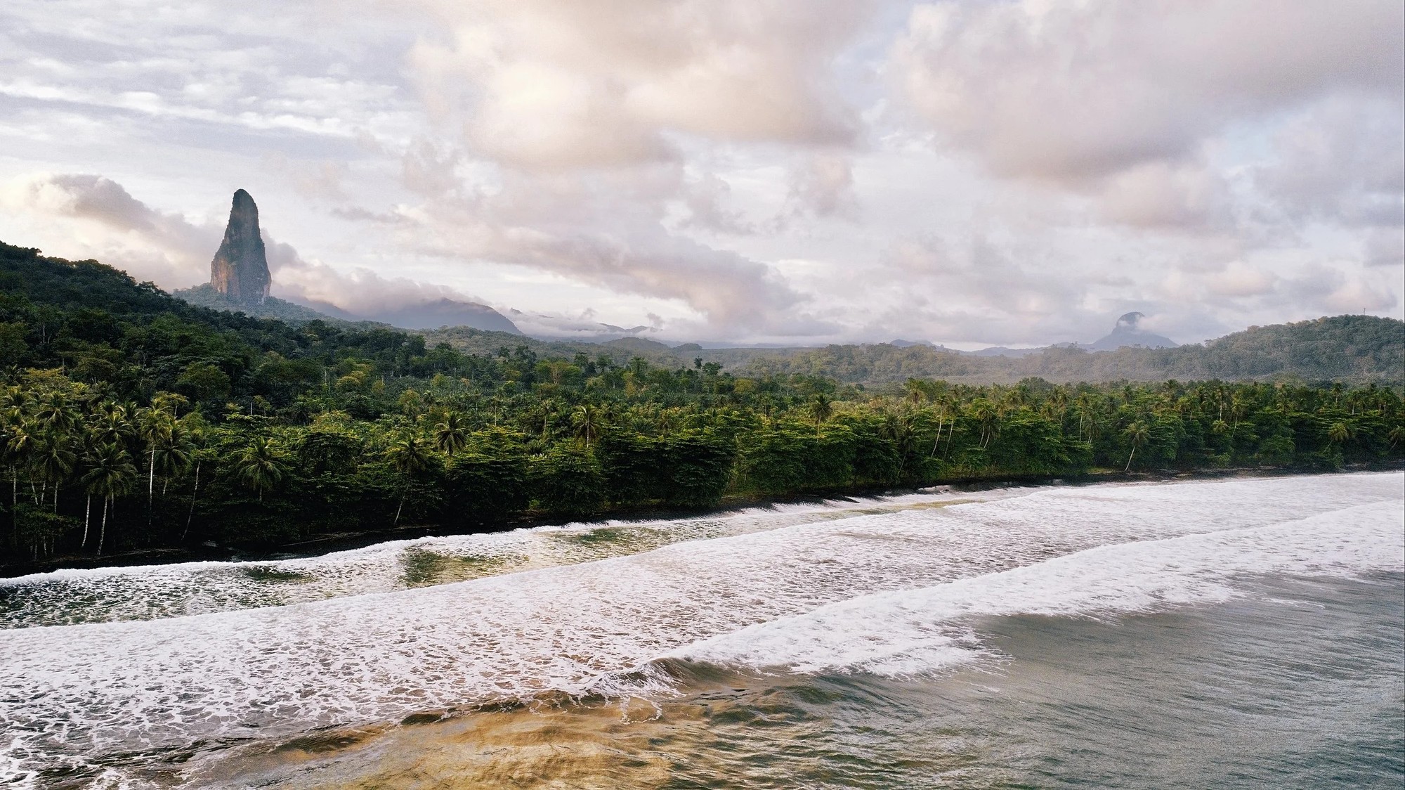 Aerial view of São Tomé's south coast with Pico Cão Grande rising over the forest