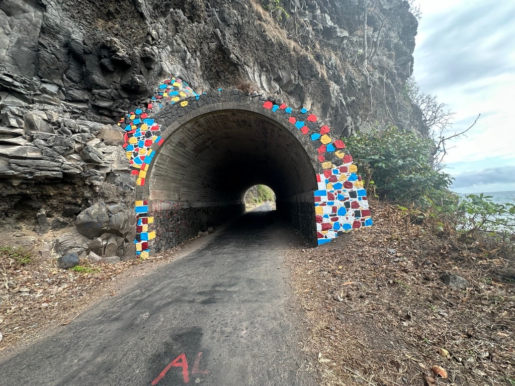 A entrada do túnel de Santa Catarina com arco em pedra pintada de cores vivas cortado na rocha vulcânica da estrada norte de São Tomé