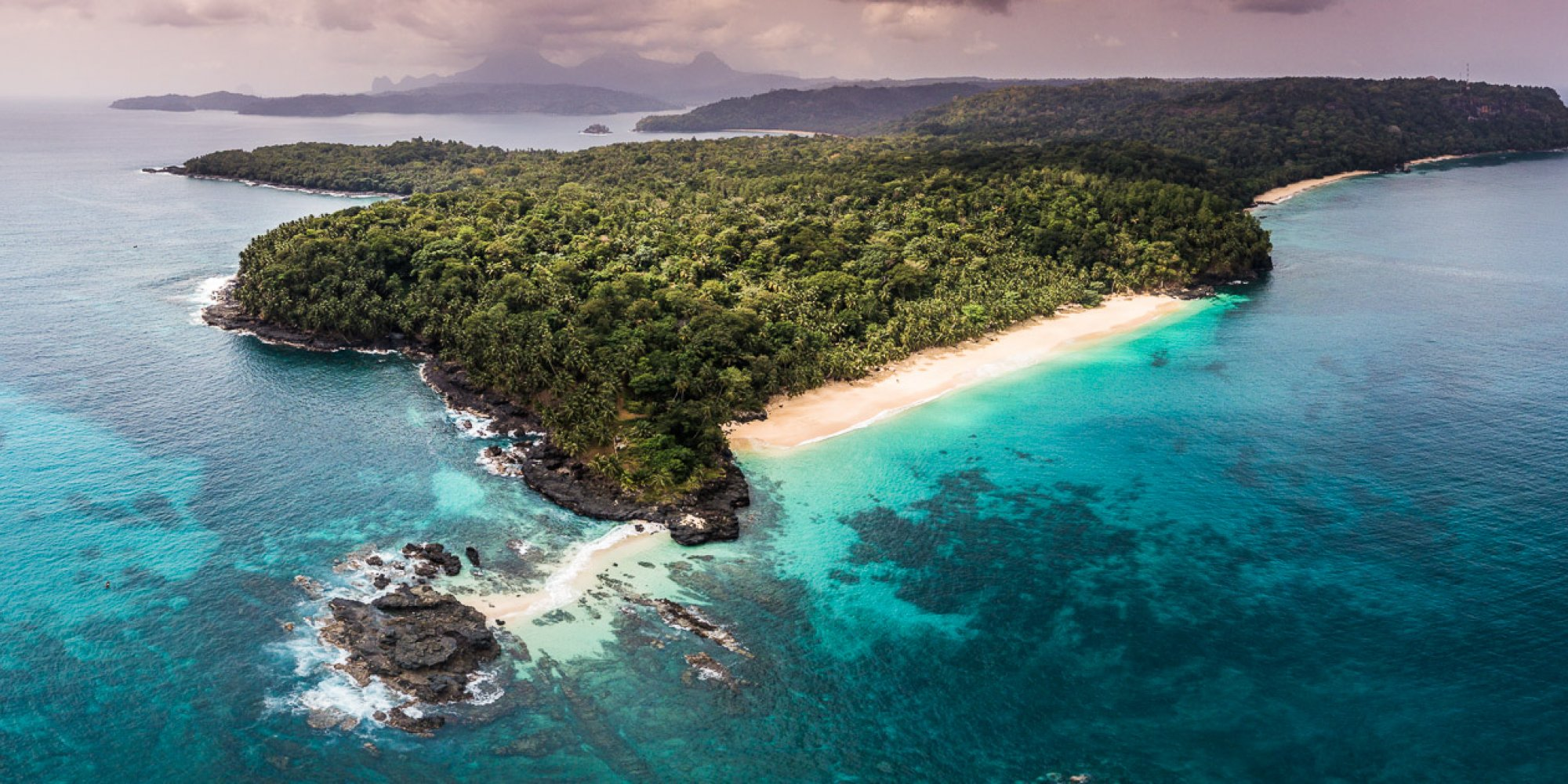 Aerial view of a forested peninsula on Príncipe with turquoise water and white sand beach