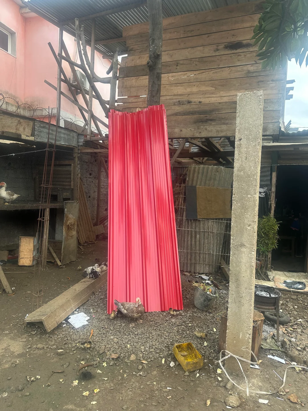 Novas chapas de telhado vermelhas prontas para reparações numa casa em São Tomé
