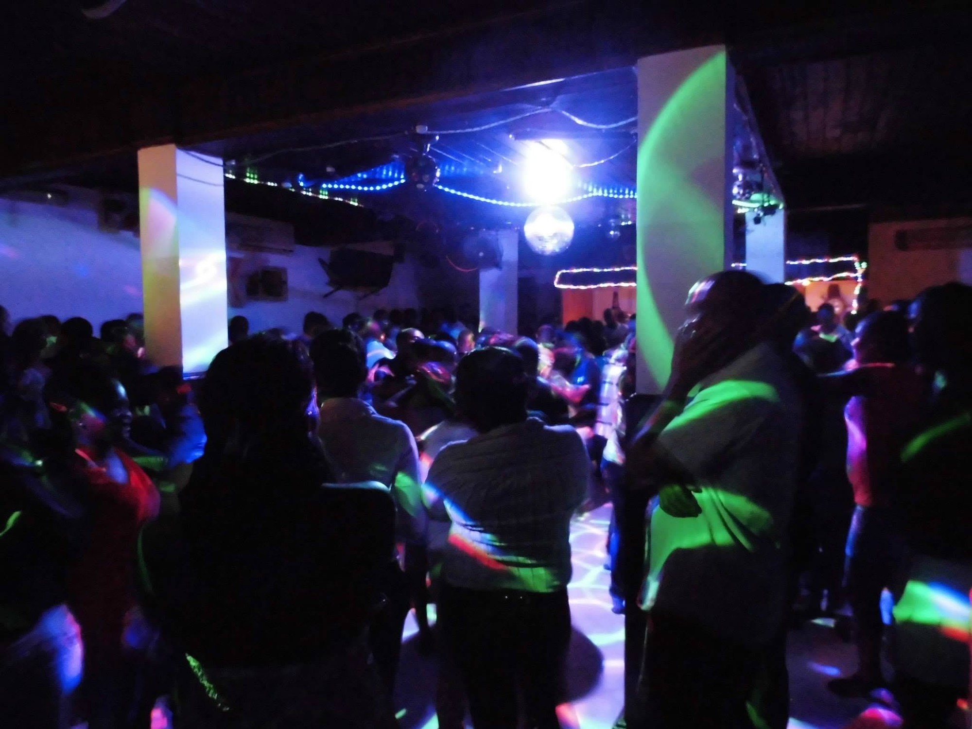 Packed dance floor inside Kizomba nightclub in São Tomé, coloured lights and mirror ball overhead
