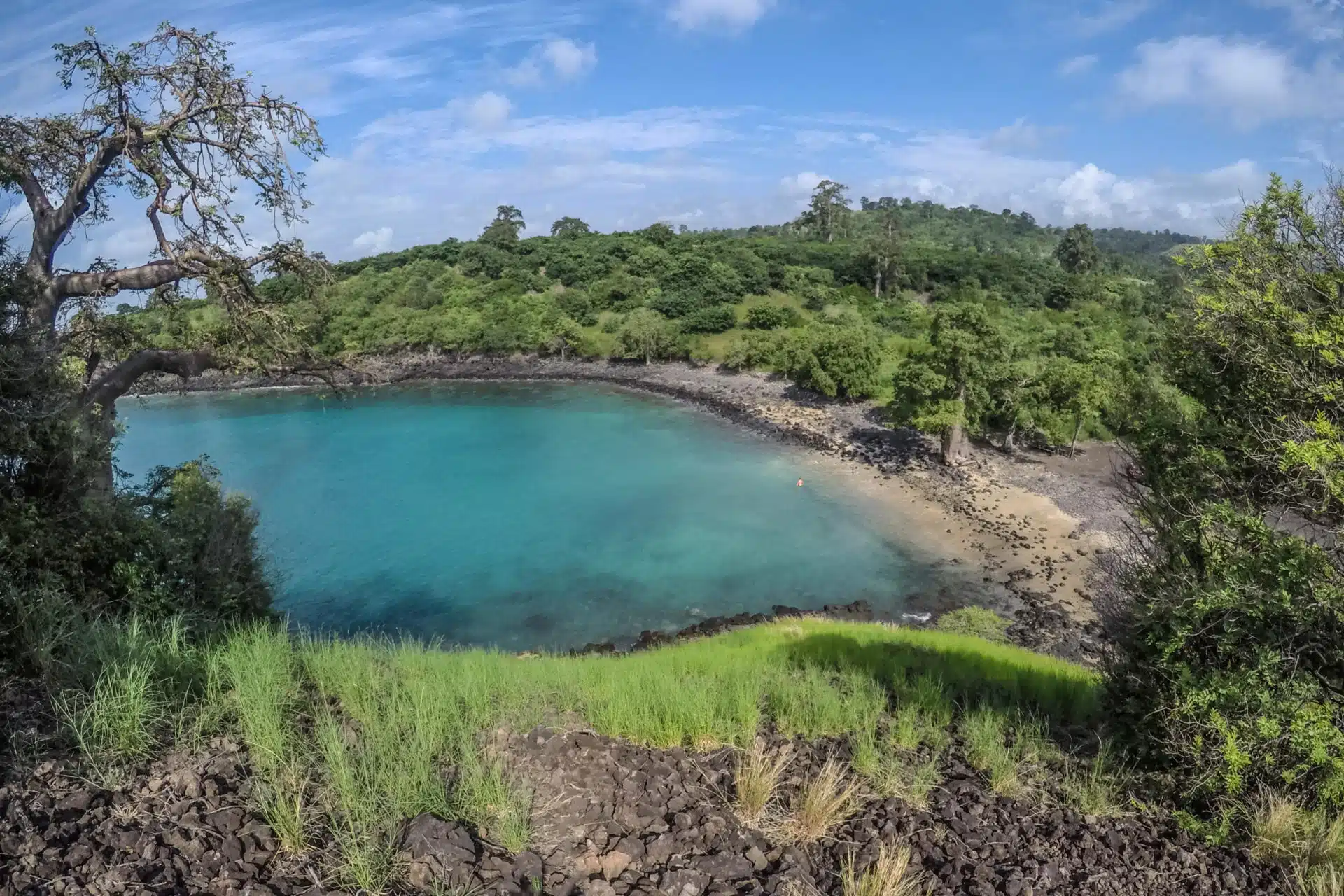A lagoa turquesa da Lagoa Azul na costa norte de São Tomé, com um promontório rochoso e árvores