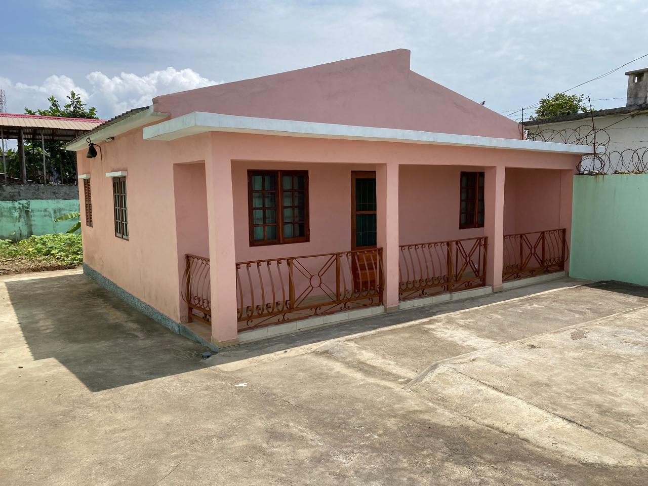A casa de Pantufo, uma casa pintada de rosa com varanda coberta e grades de ferro ornamentadas em Pantufo, São Tomé