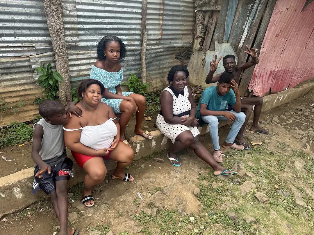 Inês, Anésia e família sentados num degrau à porta de casa em São Tomé