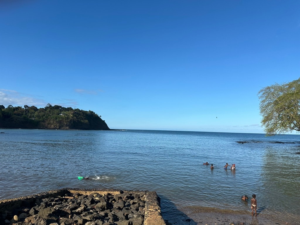 Children swimming in calm water at Santana harbour on a clear blue-sky day
