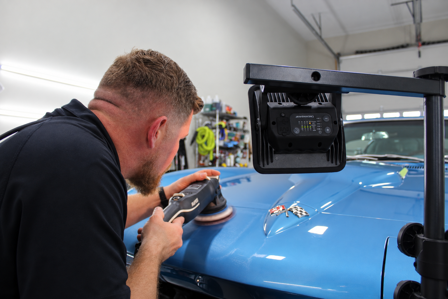 A detailer pressure-washing a black luxury car inside the Revival Autoworks studio