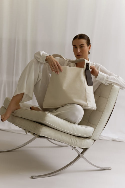 MAIIT linen tote held by a model seated on a daybed in a bright studio