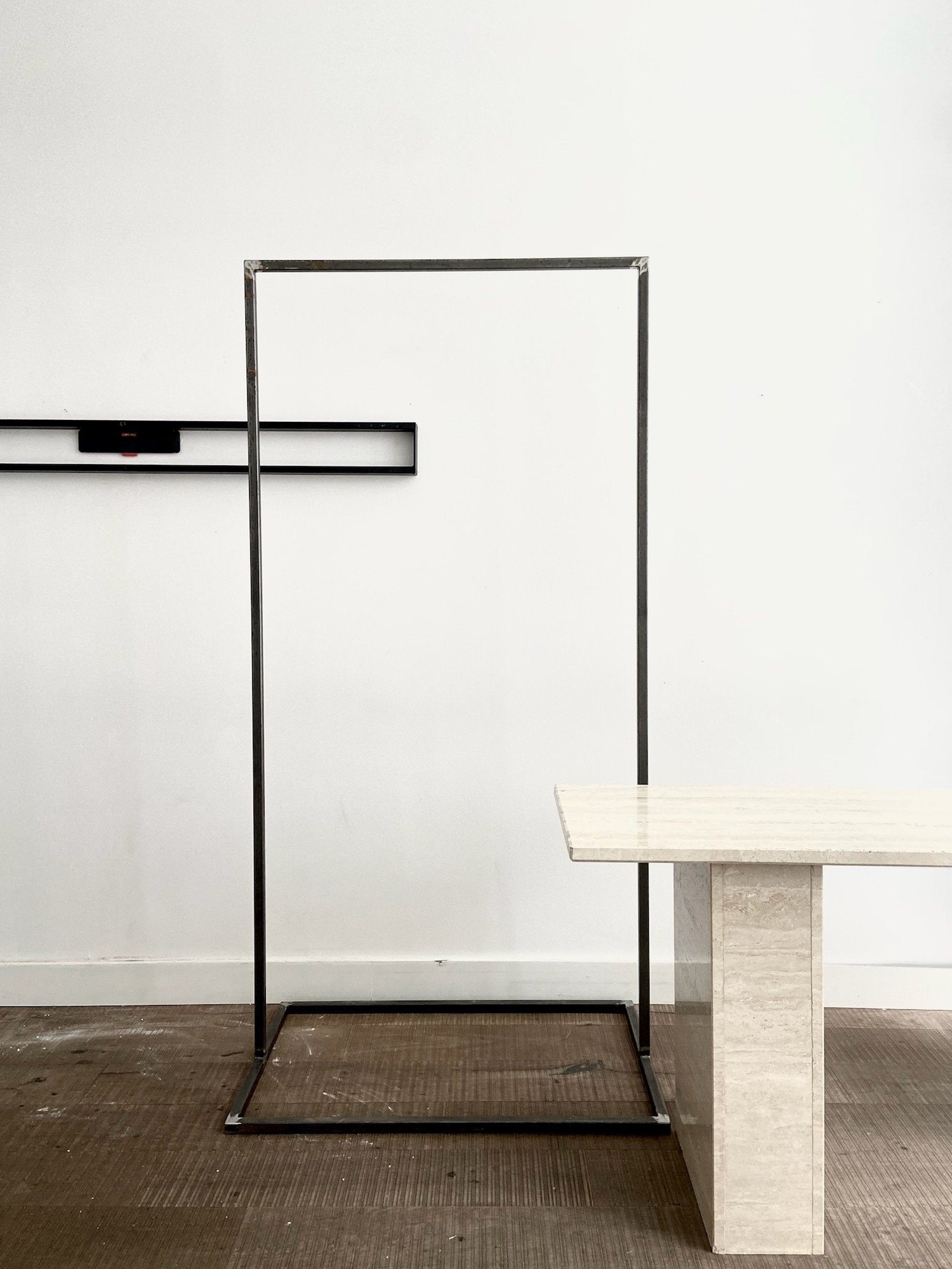 Minimal steel clothing rack and travertine table inside the Beauty with Less store