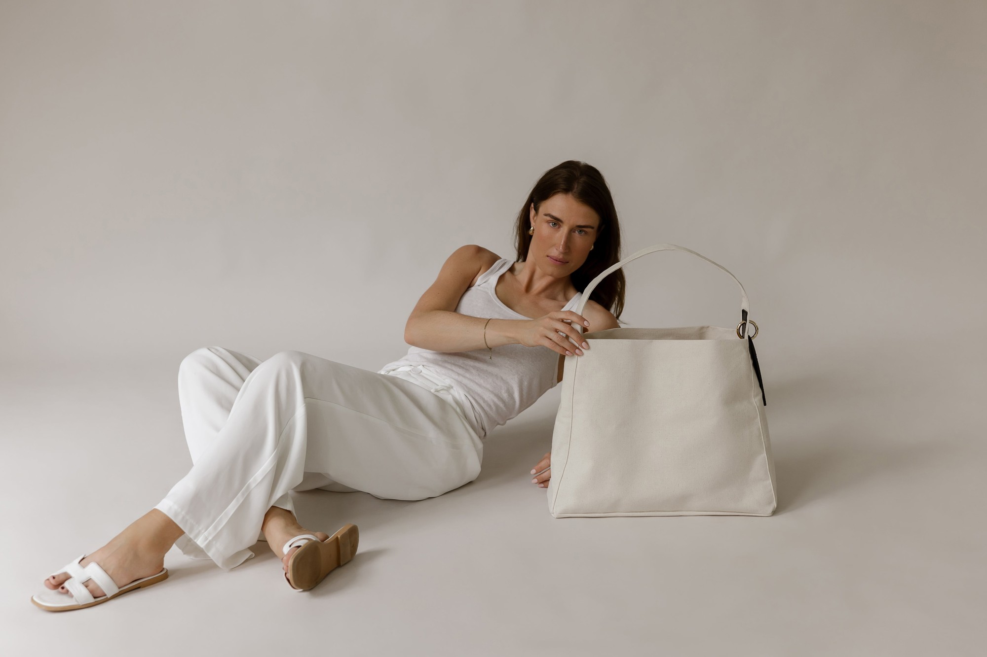 Model resting beside the MAIIT linen tote in a soft daylight studio