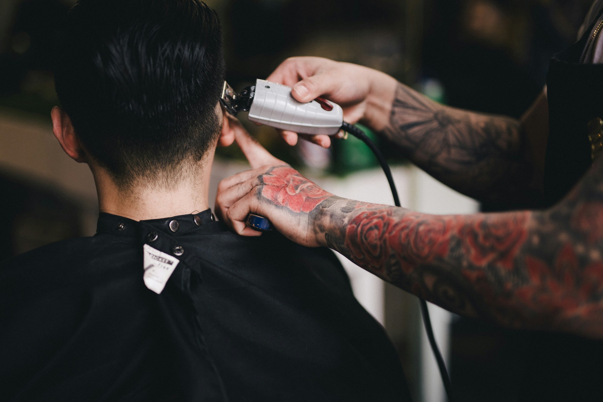 Tattooed barber cleaning up a neckline with clippers