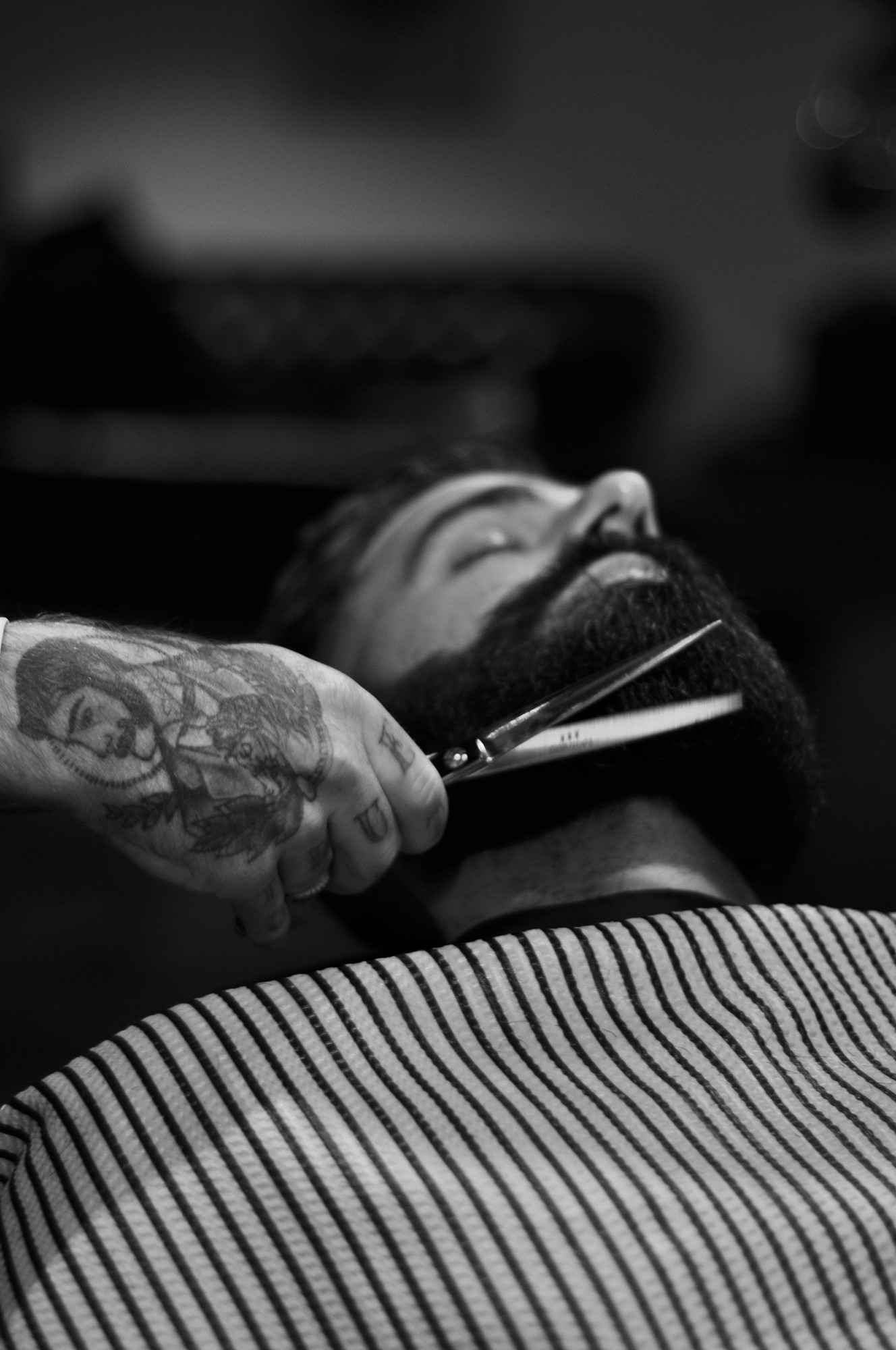 Barber trimming a full beard with scissors, shot in black and white