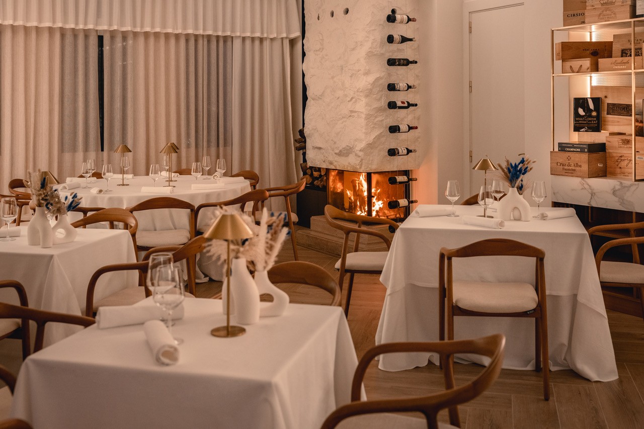 The warm interior of El Lago with a lit fireplace and candlelit tables
