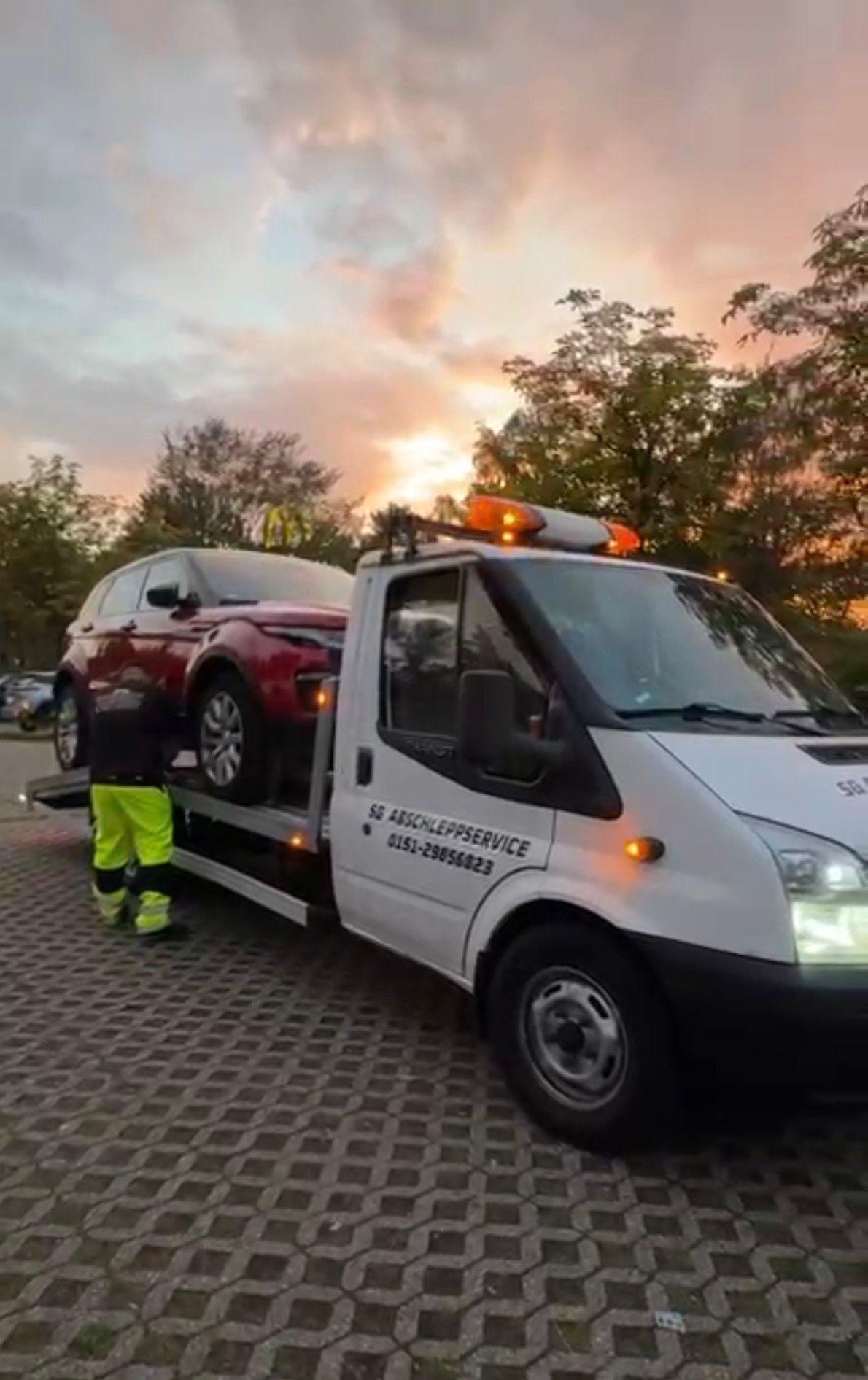 SG Abschleppservice lädt ein Fahrzeug bei Sonnenuntergang auf