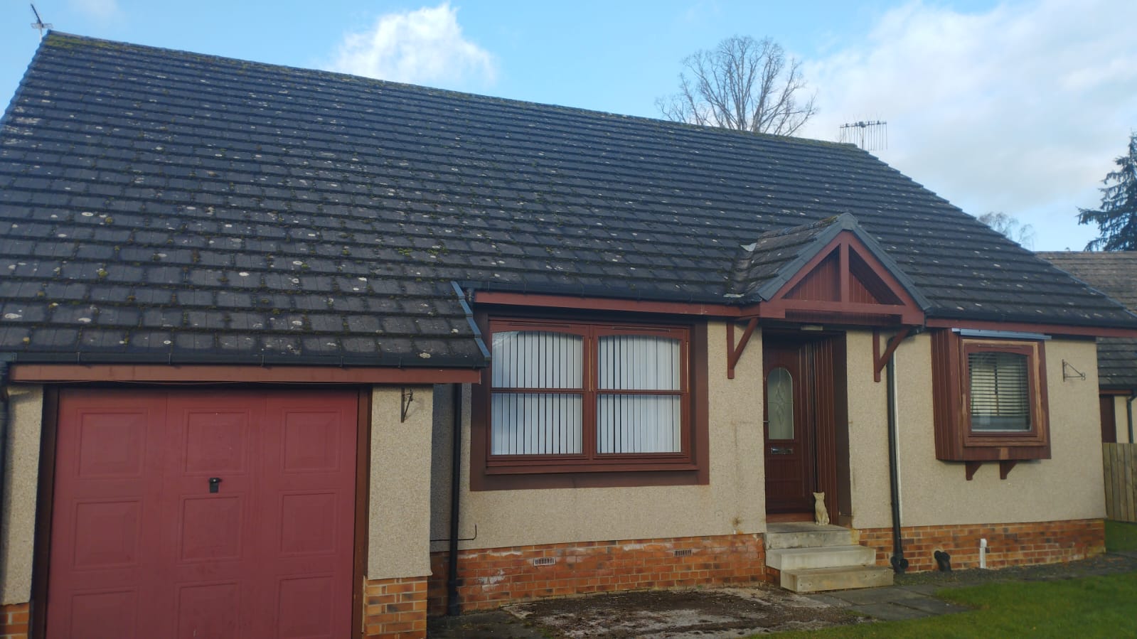 Bungalow roof before roof cleaning — lichen and moss on dark concrete tiles, Perthshire