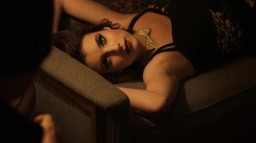 Emma Roberts reclining on a couch in a dimly lit room in Adult World