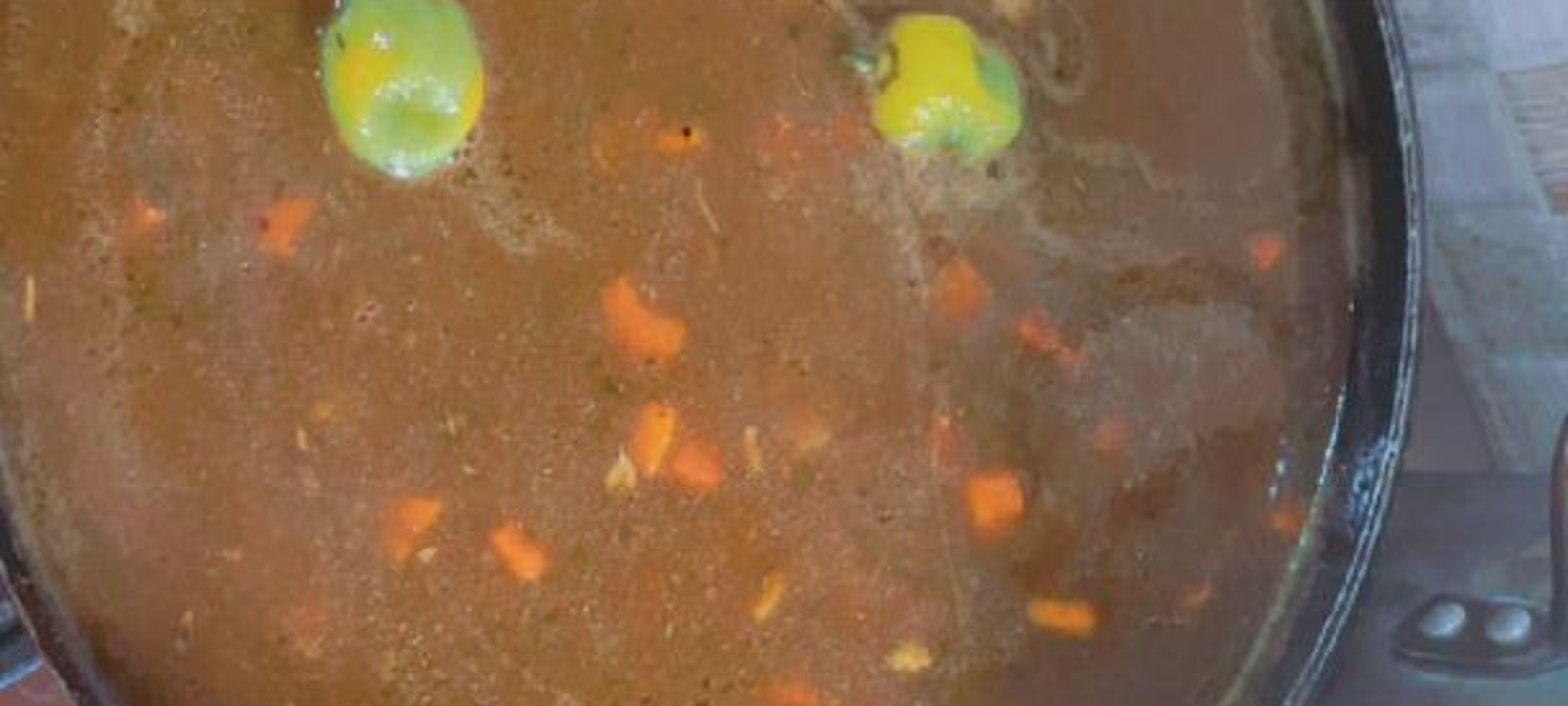 Large pan of stew with carrots and peppers cooking on the stove