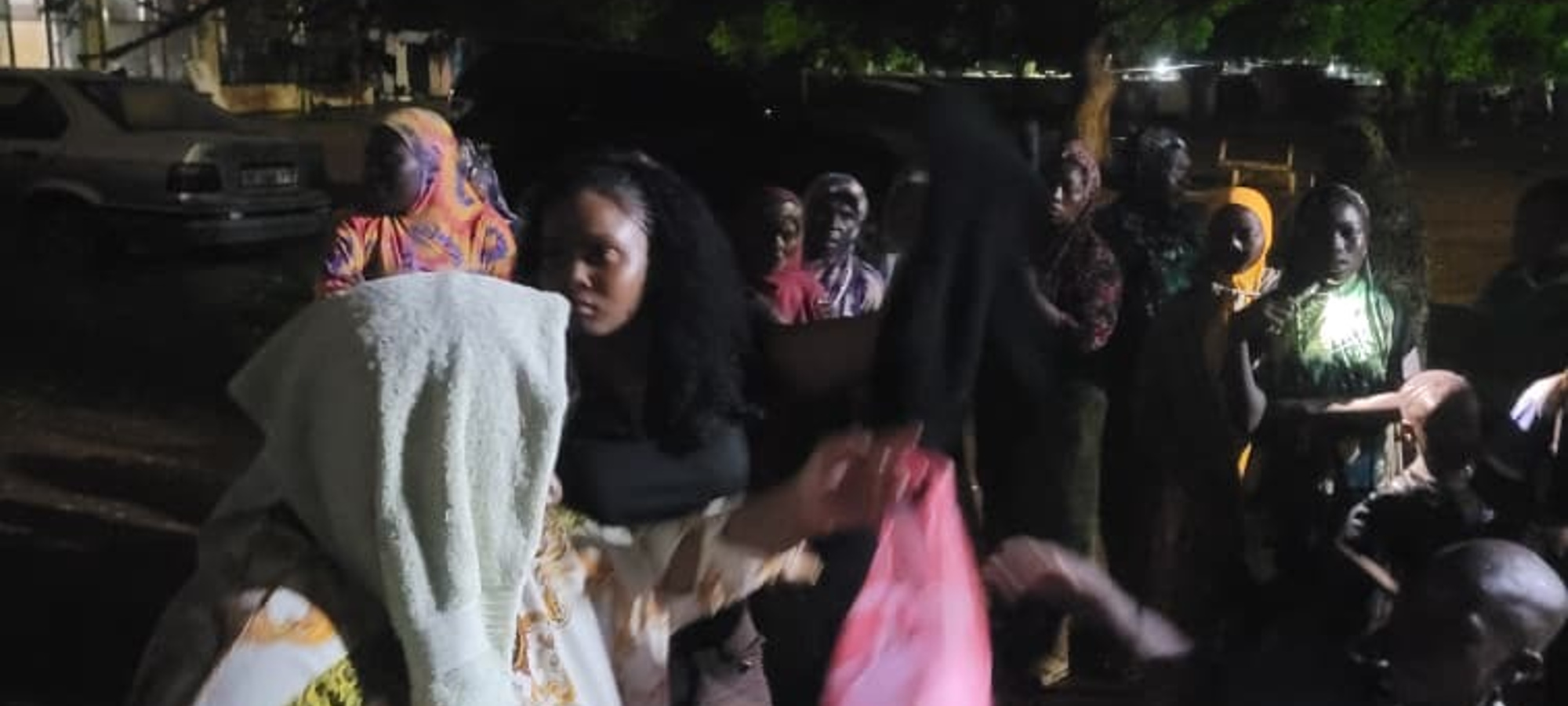 Volunteer handing out food bags to community members gathered at night