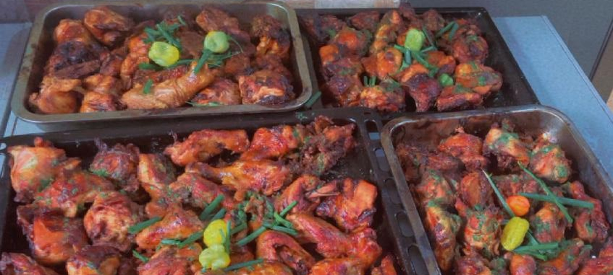 Trays of freshly cooked spiced chicken prepared for distribution