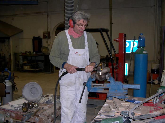 Erik Lemcke arbejder med en bronzeskulptur i skruestik på værkstedet