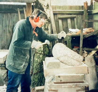 Erik Lemcke hugger en granitskulptur med hammer og mejsel