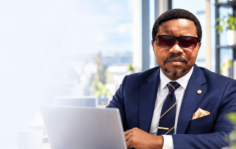 Emmanuel, a retired school principal in a navy suit, working on his laptop