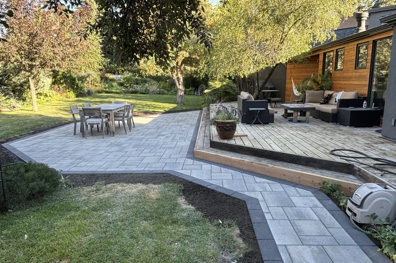 Paver patio with wooden deck and garden by All The Moore Landscaping