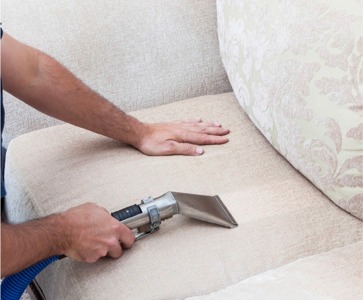Technician steam cleaning a sofa