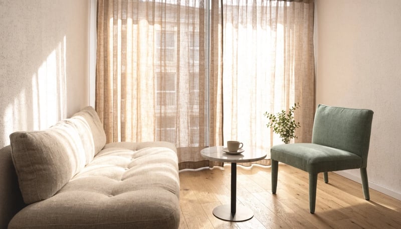 Sala de terapia con sofá beige, sillón salvia y luz natural