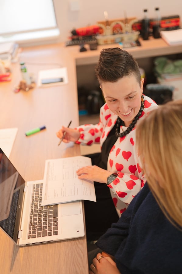 Lesgever helpt kind bij schriftelijke opdracht