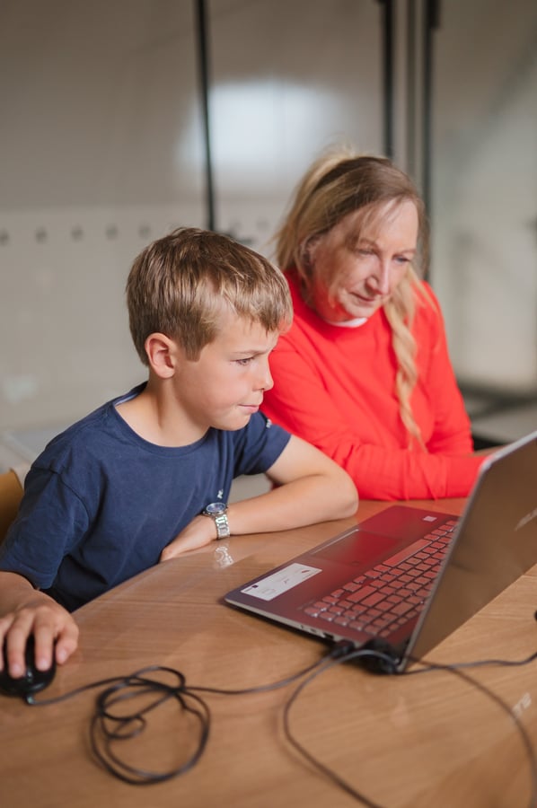 Lesgever begeleidt leerling aan de computer